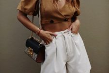 a fashionable outfit with a rust-colored cropped blouse with puff sleeves, white Bermudas, a two tone bag is wow