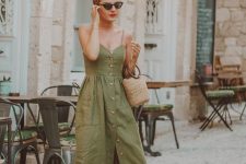 a grene linen midi sundress with spaghetti straps and buttons and pockets, a straw bag, nude slippers
