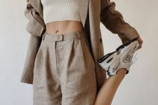 a grey linen suit with an oversized blazer and long Bermudas, a neutral crop top and neutral trainers