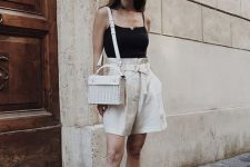a hot day outfit with a black spaghetti strap top, neutral high waisted linen Bermudas, brown slippers and a neutral woven bag
