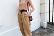 a rust-colored linen top, tan colored linen pants, black birkenstocks, a black belt and a brown bag are a hot day