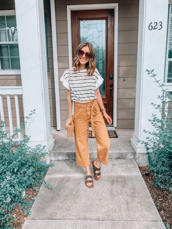 a striped t-shirt, tan paperbag waist cropped pants, black birkenstocks and a woven bag