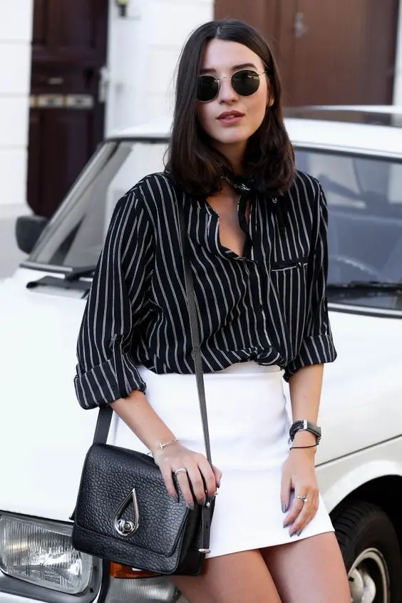 a stylish work appopriate look with a black striped shirt, a white mini, a black bag and some bracelets