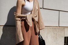 a summer work outfit with a white halter neckline top, a tan linen shirt and rust-colored linen shorts plus a black bag