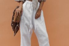 a vacation look with a grey tied up cropped blouse with puff sleeves, white cropped pants, white slippers and a woven bag