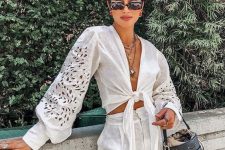 a vacation look with a white linen crop blouse with puff sleeves, high waisted linen shorts and a black bucket bag