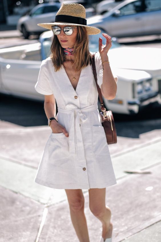 a white linen button up mini dress with a V neckline and pockets, a hat, a brown round bag and a neck tie
