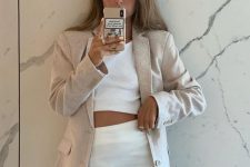 a white linen crop top and a matching A-line mini skirt with a slit, a neutral linen blazer and a necklace to look sexy
