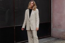 a white linen pantsuit with an oversized blazer, a black t-shirt and black dad sandals for a chic and comfortable summer work look