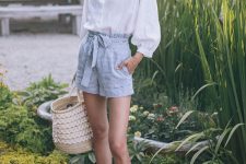 a white linen shirt, blue gingham shorts, brown slippers, a woven bag with lace