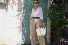 a white linen shirt, neutral linen wideleg pants, a brown belt, heels and a white bag