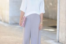 a white loose top with short sleeves, lilac culottes, a pink clutch and colorful lace up shoes