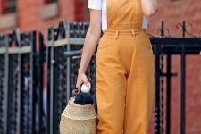 a white t-shirt, a sunny yellow overall, grey birkenstocks, a woven bag for a cute summe rlook