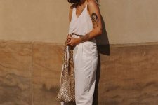 a white top, white trousers with pockets, black block heels, a woven bag and statement earrings