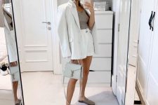an elegant and chic summer work look with a grey top and a white linen short suit, grey slipper mules and a light grey bag is ultimate