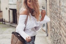 an off the shoulder white blouse with long bell sleeves, a blue A-line denim mini and a woven bag for summer