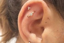 stacked ear piercings including two lobe ones, a helix and a flat orbital piercing with chic and bold earrings