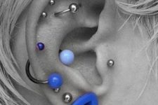 stacked earing piercings including a flat orbital, tragus, several helix and lobe piercings and super bold jewelry
