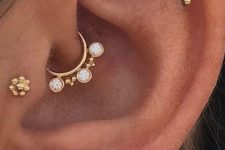 04 chic ear styling with a daith, tragus, a double lobe and flat piercing done with cool gold studs and a hoop earring