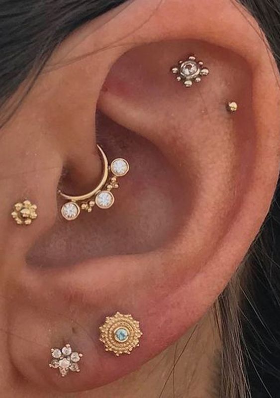 chic ear styling with a daith, tragus, a double lobe and flat piercing done with cool gold studs and a hoop earring