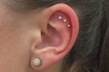12 a cool triple flat piercing done with matching studs of mismatching sizes and a large stud earring in the lobe to finish the look
