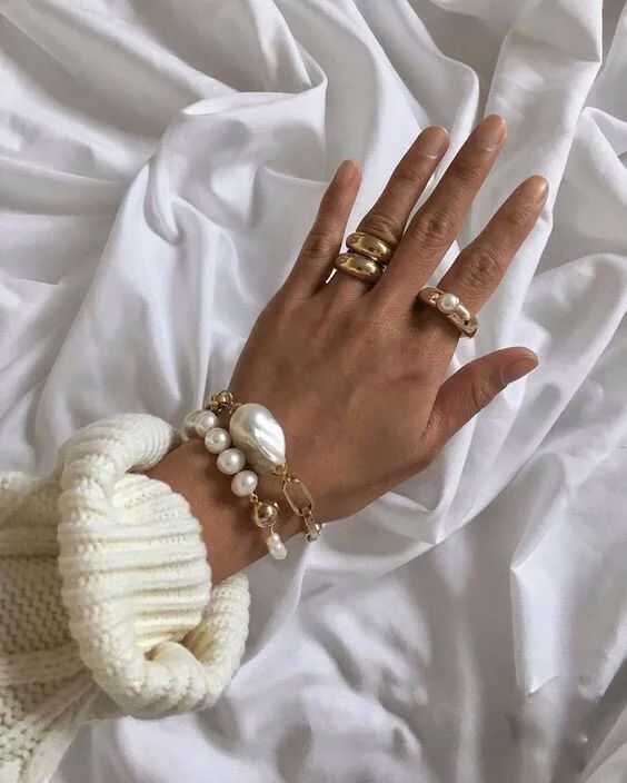 fantastic stacked bracelets of chain and usual and baroque pearls and statement gold rings with pearls, too