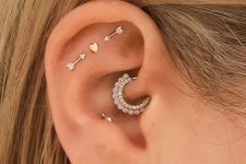 20 creative ear styling with a triple flat, daith, conch and lobe piercing, with heart and arrow studs and a rhinestone hoop