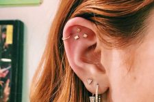 26 stylish stacked piercings – a double lobe piercing, a helix and a triple flat piercing, all done with rhinestone studs and hoops