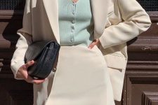 a beautiful creamy skirt suit with a mini, a green button up top and a black saddle bag is chic and cool
