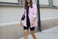 a black t-shirt, black biker shorts, a pink oversized blazer, pink and black trainers and a black crossbody bag
