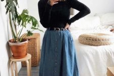 a black turtleneck, a blue denim midi A-line skirt, black flat shoes and a black belt for a retro-inspired look
