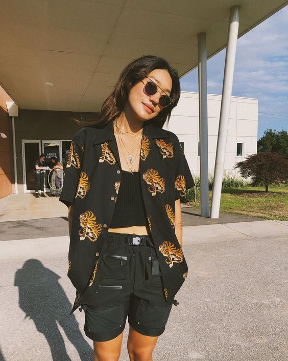 a bold look with a black crop top, black cargo shorts, a black printed shirt and sunglasses to stand out a lot