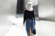 a casual outfit with a navy sweater, a blue denim button up midi, white sneakers and a black backpack