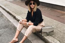 a chic look with a black shirt, tan pants, beige slipper mules, a matching hat and a grey bag is very pretty