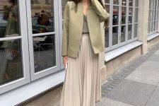 a chic outfit with a green top, a green sleek blazer, a grey pleated midi and Oxford shoes for an accent