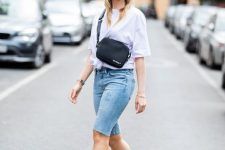 a chic outfit with a white tied up tee, blue denim biker shorts, a bucket hat, a black bag and sheer heels