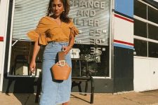 a mustard-colored blouse with ruffle sleeves, a blue denim midi, gold mules, a brown bucket bag is amazing