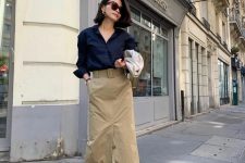 a navy shirt, a beige midi skirt with buttons and a belt, white loafers and a white bag for a cool look