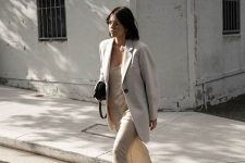 a neutral slip maxi dress, a creamy oversized blazer, white trainers and a black bag for a minimalist look