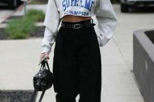a printed cropped hoodie, black barrel jeans, a belt, a black bag and white sneakers