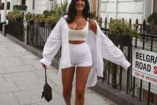 a sexy and sporty look with a neutral crop top and biker shorts, an oversized white shirt, white platform sneakers and a black bag