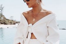 a simple and chic vacation outfit with a tied up crop top with short sleeves, high waisted shorts and a statement necklace