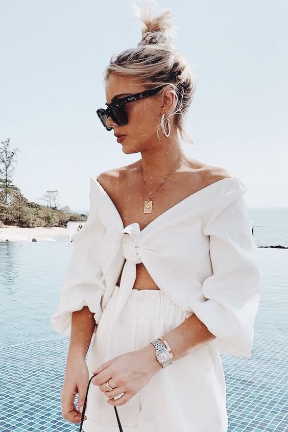 a simple and chic vacation outfit with a tied up crop top with short sleeves, high waisted shorts and a statement necklace