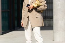 a simple and work-appropriate outfit with a white t-shirt, white jeans, a tan oversized blazer, white heels and a gold bag