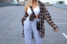 a sport chic outfit with a white crop top, grey sweatpants, white trainers, a plaid shirt and a black bag