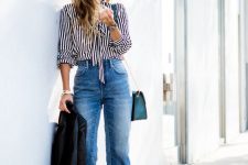 a striped shirt, blue cropped flare jeans, high heels, a blue bag and a black jacket