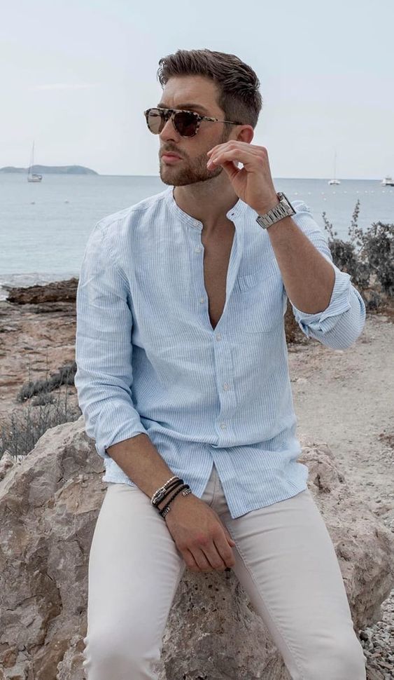 a stylish coastal outfit with a blue striped linen shirt, tan jeans, stacked bracelets and a cool watch