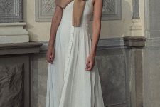 a white A-line maxi dress with buttons and slits, metallic sliders and a tan sweater for colder weather
