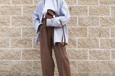 a white halter neckline top, brown trousers, a pale blue oversized shirt, brown slippers and a bag