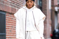 an athleisure inspired look with a white cropped hoodie, sweatpants, a vest, a black beanie